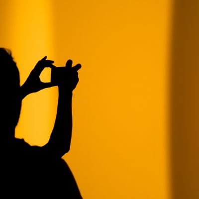 Shadow of a man holding a camera on an orange background 